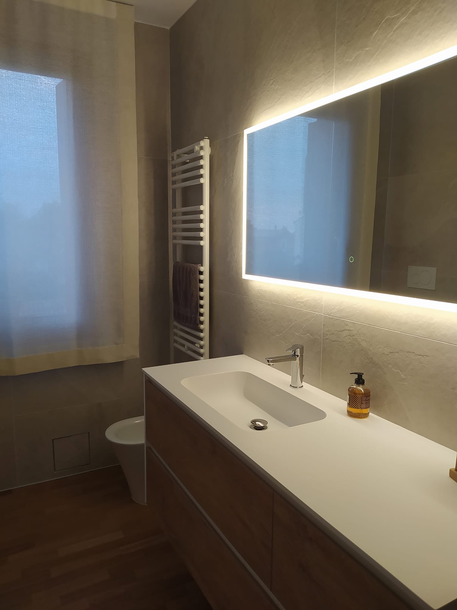 Bagno realizzato con lavabo integrato e specchio retroilluminato