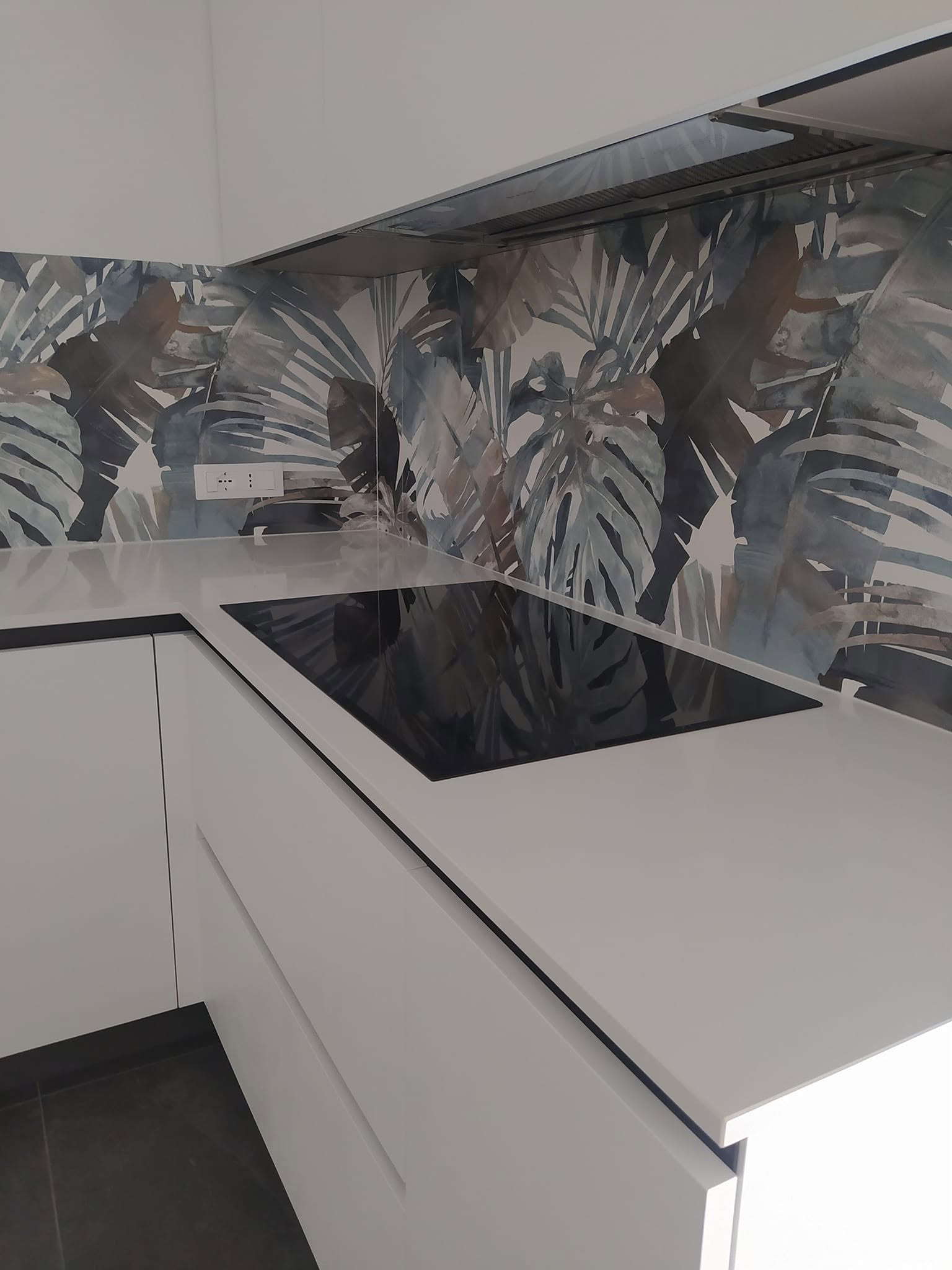 Cucina realizzata con piano chiaro e rivestimento decorativo a foglie
